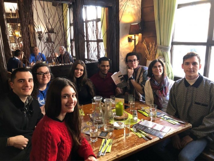 Students are seated around a table in a German restaurant smiling for their group picture.